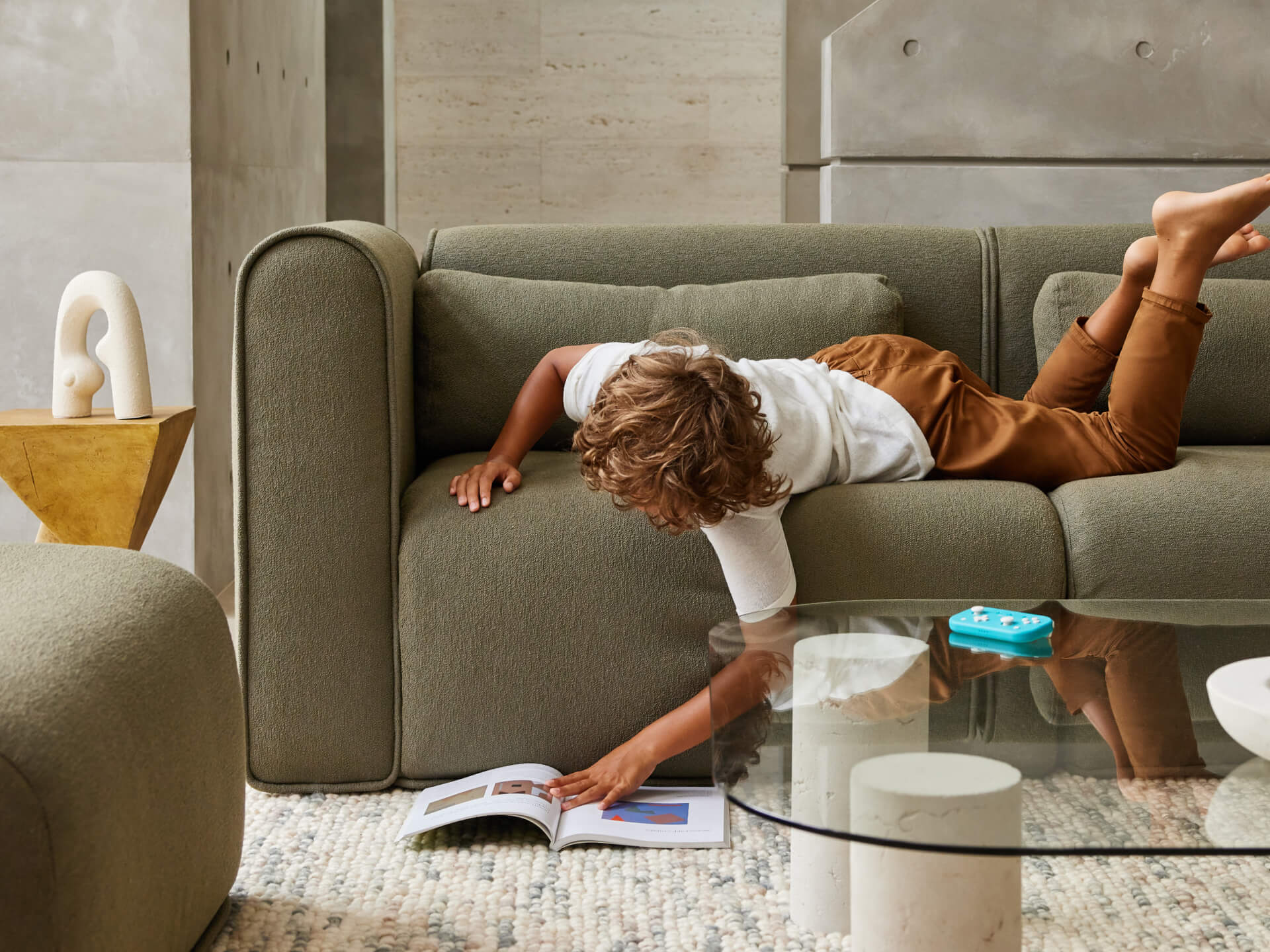 Luxurious olive green sectional sofa in plush upholstery, featuring rounded cushions and a minimalist design, set in a modern concrete-finished room.