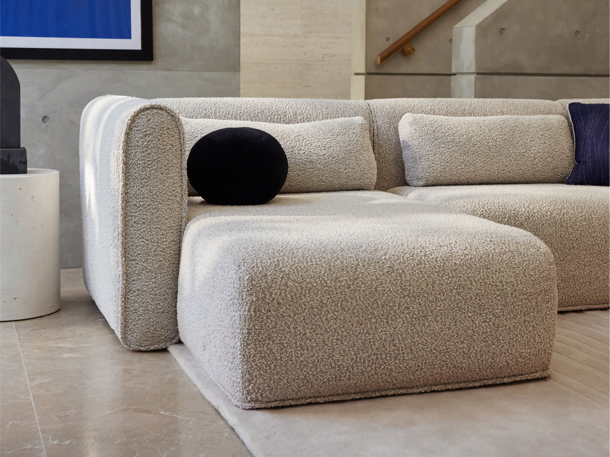 Luxurious boucle sectional sofa in soft cream, featuring plush cushions and a minimalist design, set in a chic, contemporary living room.