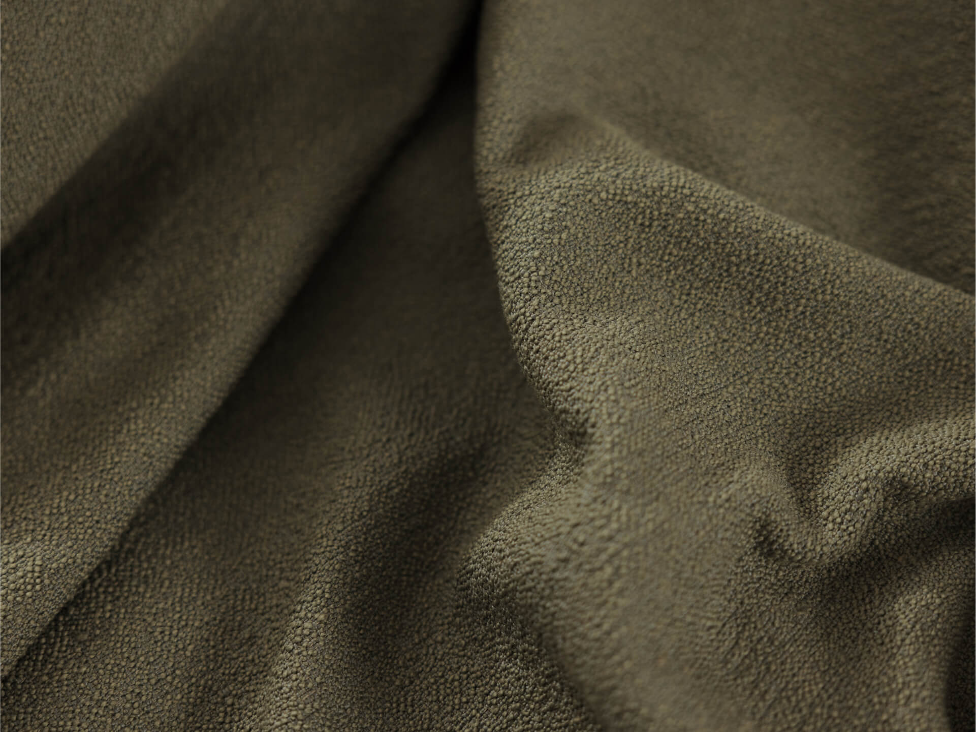 A close-up of textured fabric in olive green, with folds creating subtle shadows and highlights, showcasing its soft surface.