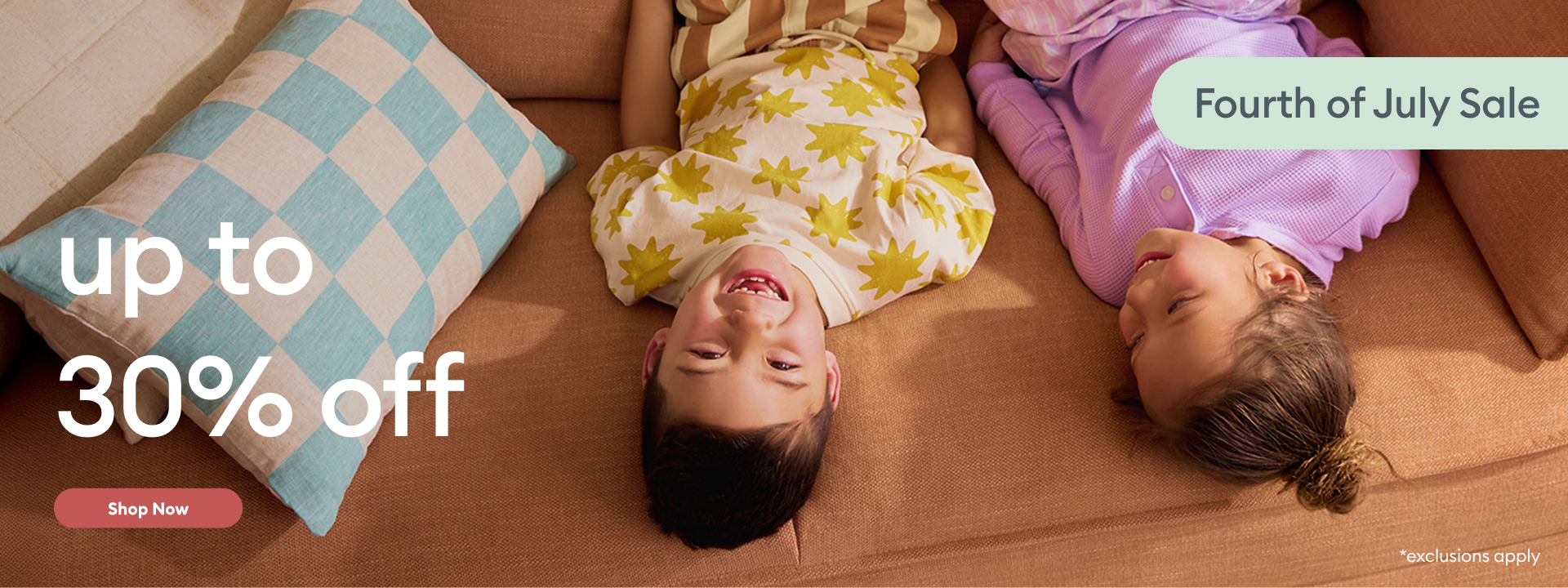 Two children lying on a couch with promotional text for a Fourth of July sale and discount offer.