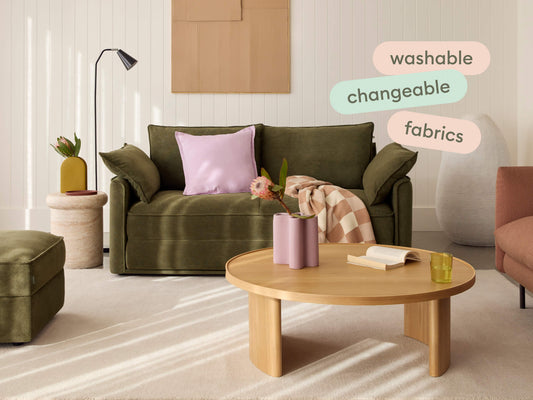 Olive green sofa in textured fabric, featuring plush cushions and wide arms. Set in a chic lounge with a light wood coffee table and neutral decor.