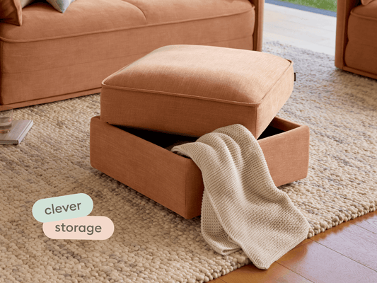 Plush ottoman in terracotta fabric, featuring hidden storage and soft textured finish. Set on a stylish woven rug, enhancing contemporary interiors.