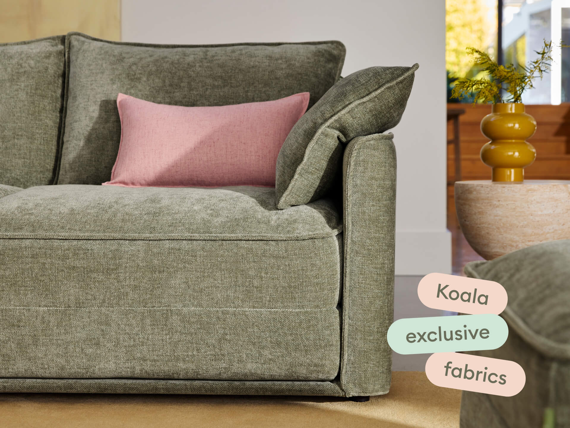 Luxurious green linen sofa with plush, deep cushions and a pink accent pillow. Set in a sunlit living room with modern decor and a neutral palette.