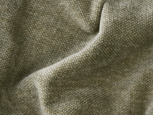 Close-up of textured beige linen fabric upholstery. The soft, woven material features a subtle, natural finish, ideal for premium sofas or armchairs.