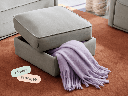 Elegant light grey ottoman with soft fabric finish, featuring a removable top for storage. Set on a rich terracotta carpet, enhancing modern living spaces.