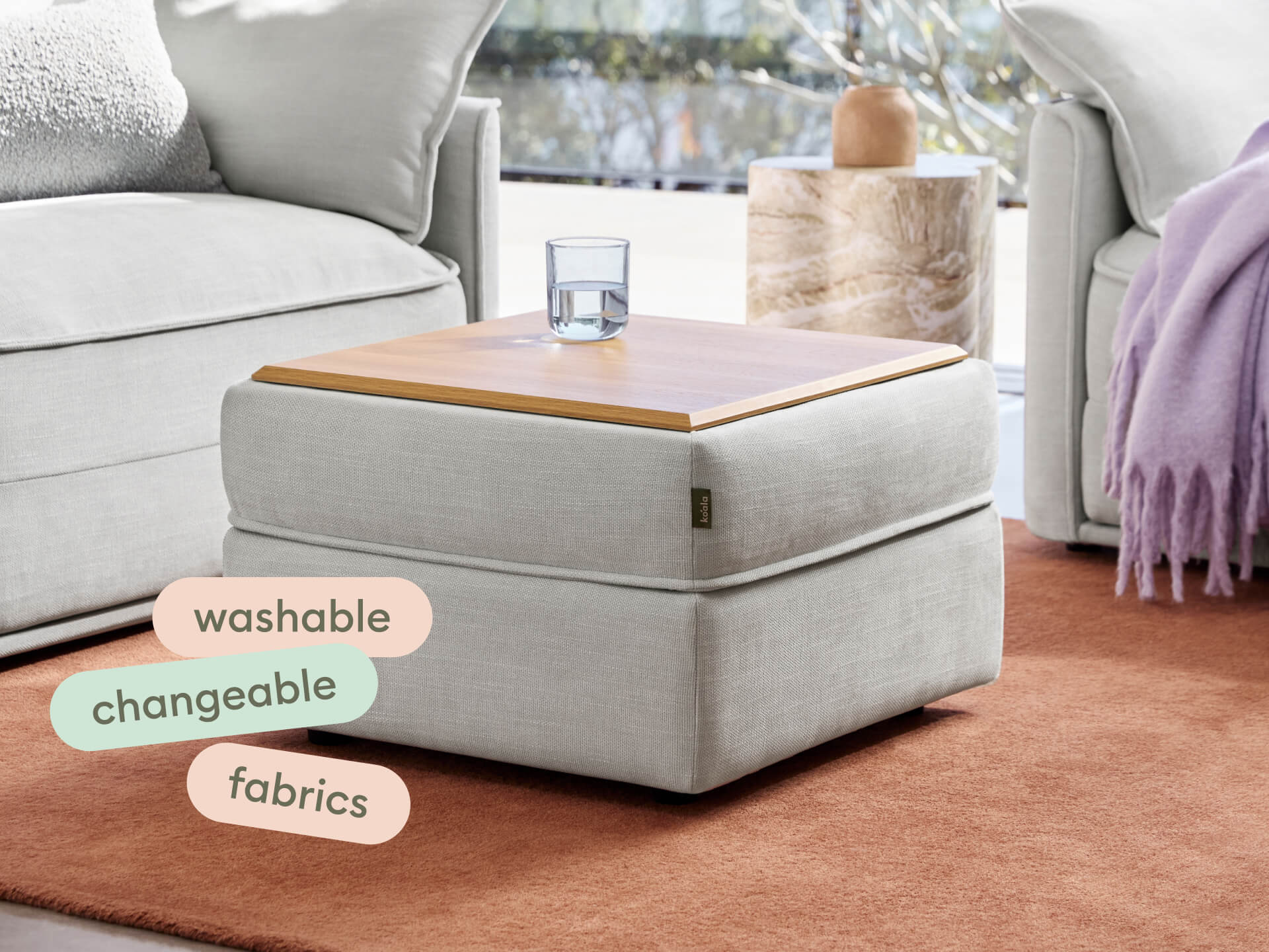 Modern ottoman featuring neutral fabric with a sleek wooden tray top, set in an elegant living room. Washable and changeable upholstery.