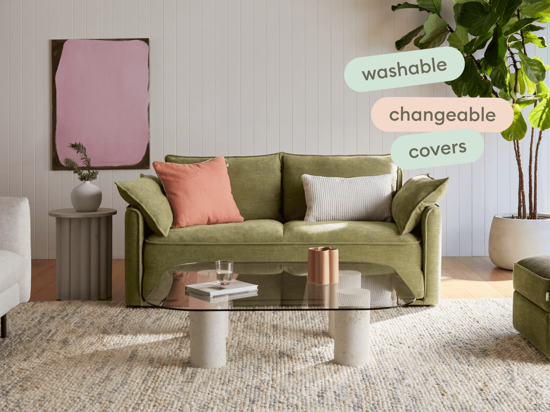 Olive green sofa with washable, changeable covers; features plush cushions on a neutral rug. Set in a modern living room with a glass coffee table.