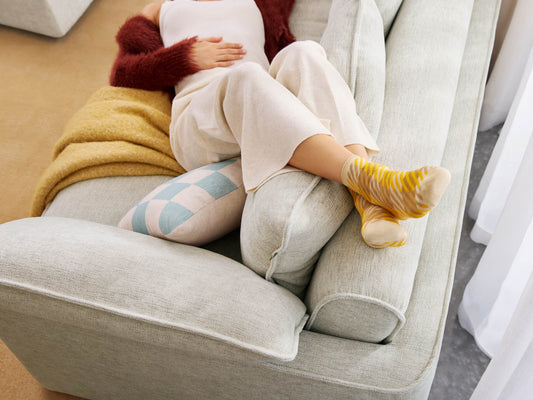 Koala Cushy Sofa Bed in sandstone with person relaxing in lifestyle setting