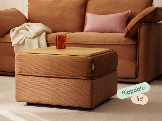 Square ottoman with textured brown upholstery and a flippable wooden lid. Styled in a cosy living room setting, complemented by a soft sofa and cushions.