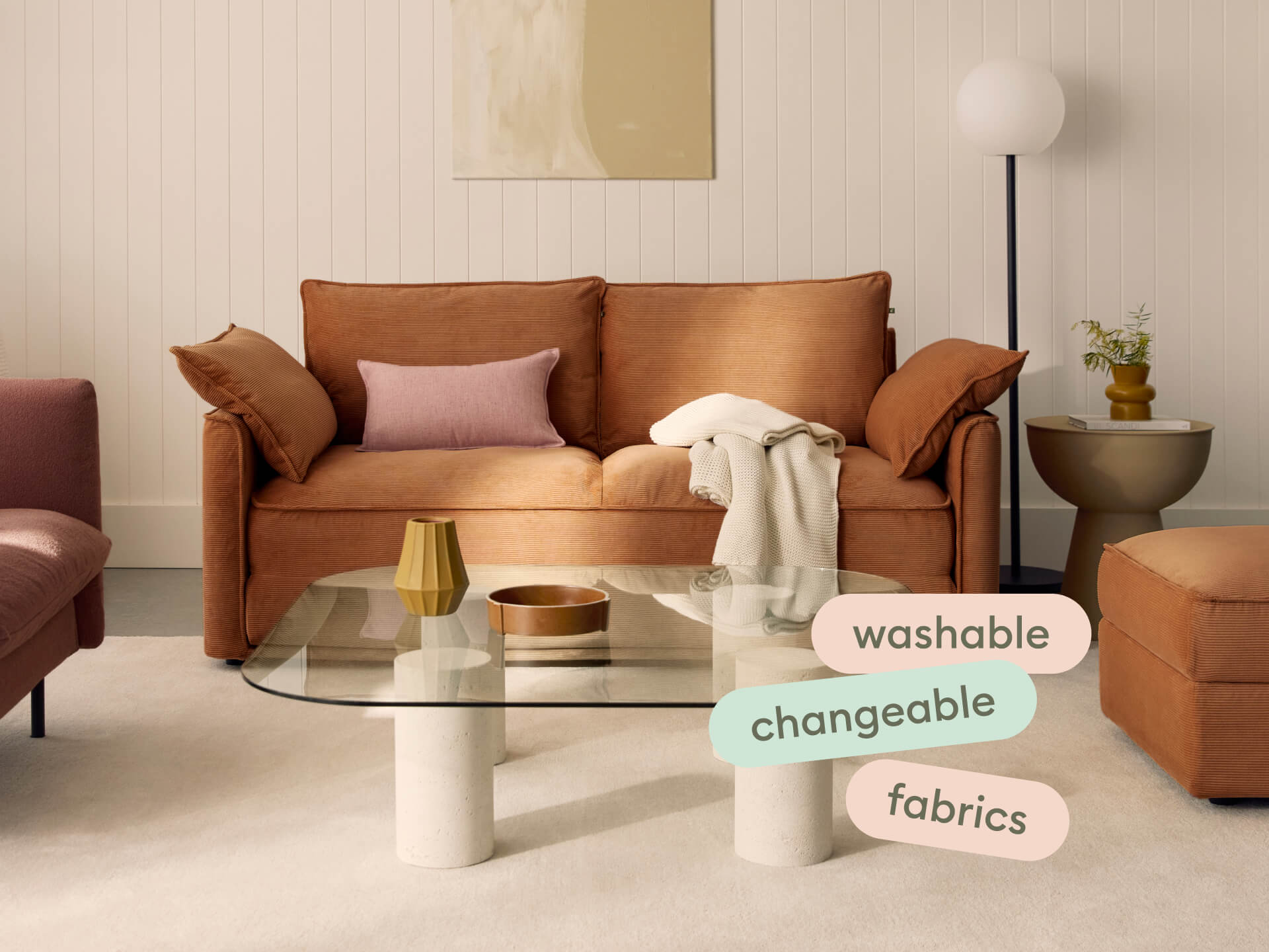 Luxurious tan sofa in a contemporary setting, featuring linen-like fabric and plush cushions. Paired with a sleek glass coffee table and modern floor lamp.
