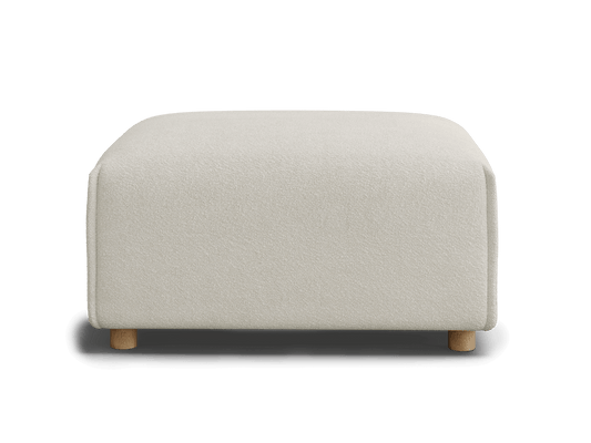 A cream-colored upholstered ottoman with a soft texture and light wooden legs, set against a black background.