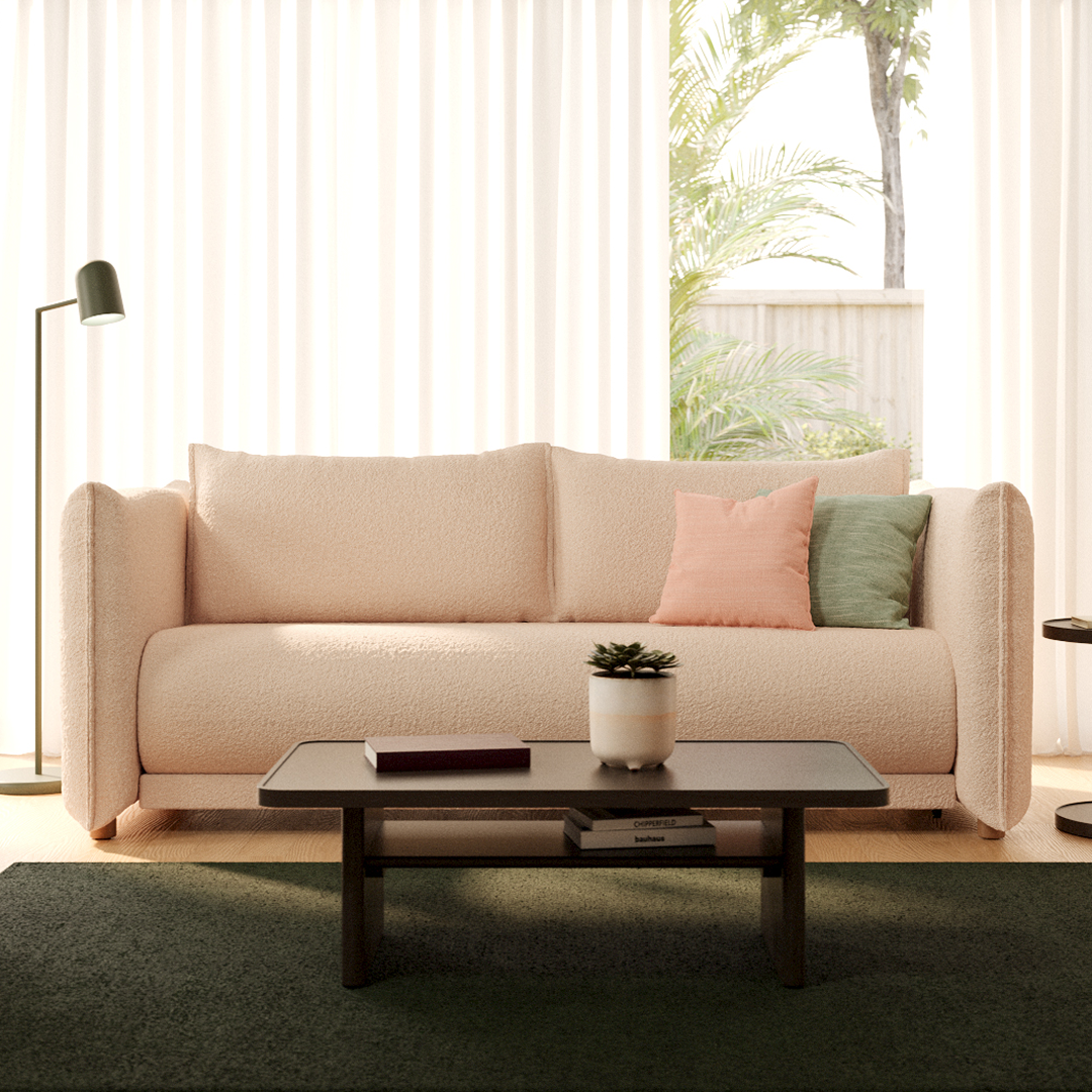 Cream boucle sofa with plush cushions, framed by sleek, modern black coffee table. Set in airy, sunlit room with lush greenery and sheer curtains.