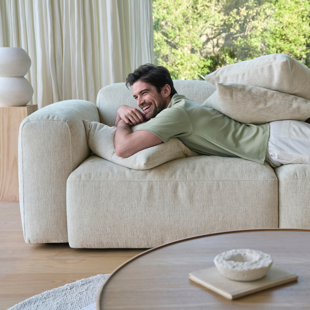 Luxurious beige linen sofa with plush cushioning and modern design, set in an airy living room with natural light and wood flooring for an elegant ambience.