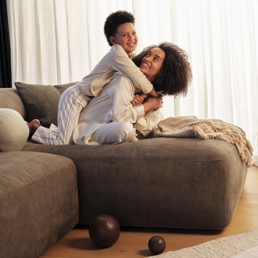 Luxurious sectional sofa in plush grey fabric, featuring deep seats and a minimalist silhouette. Set in a cosy living room with natural wood flooring.