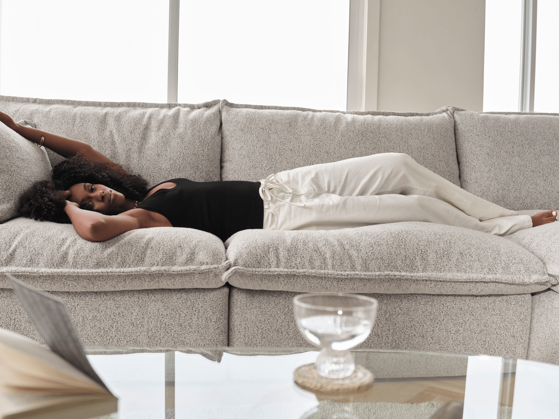 Koala Tamarama 3-section modular sofa in Aussie Latte, with model, brown knit cushion and bookshelves backdrop