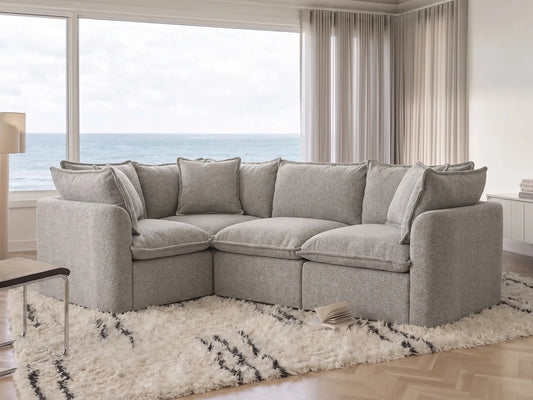 Gray sectional sofa in a living room with large windows overlooking water.