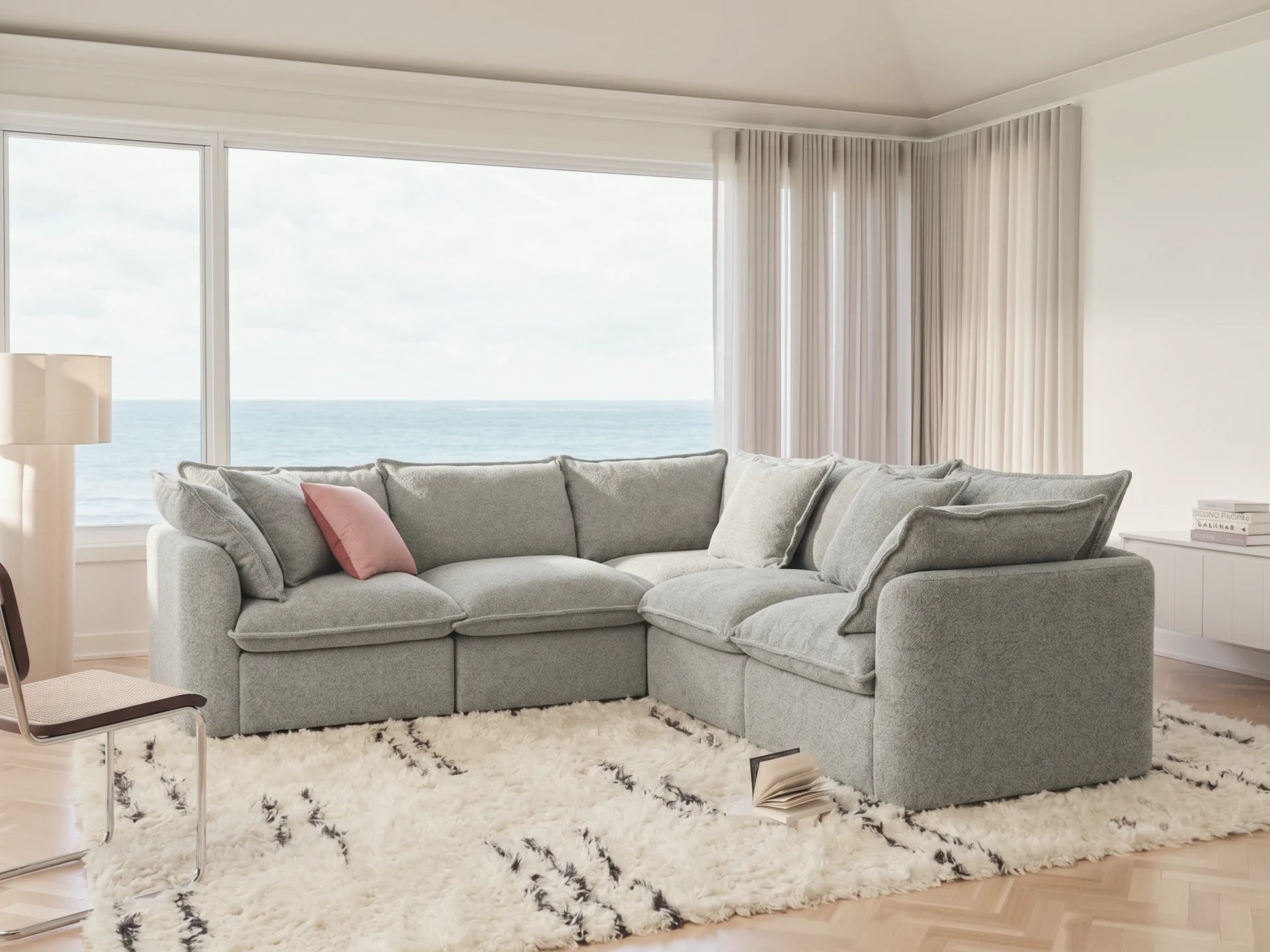 Gray sectional sofa in a living room with large windows and a view of the ocean.