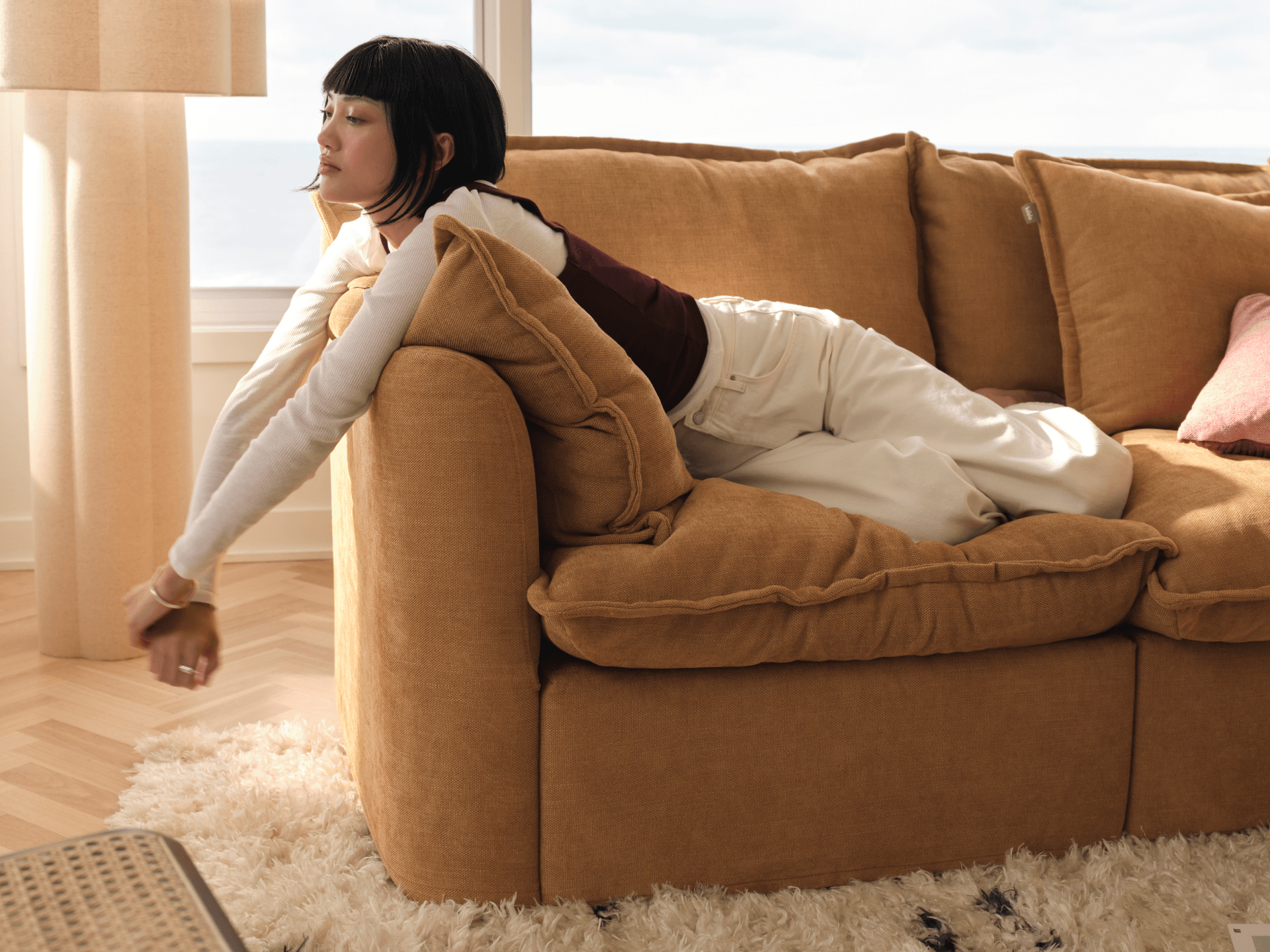 Koala Tamarama 2-section modular sofa in Bronzed Aussie, with model, brown knit cushion and bookshelves backdrop
