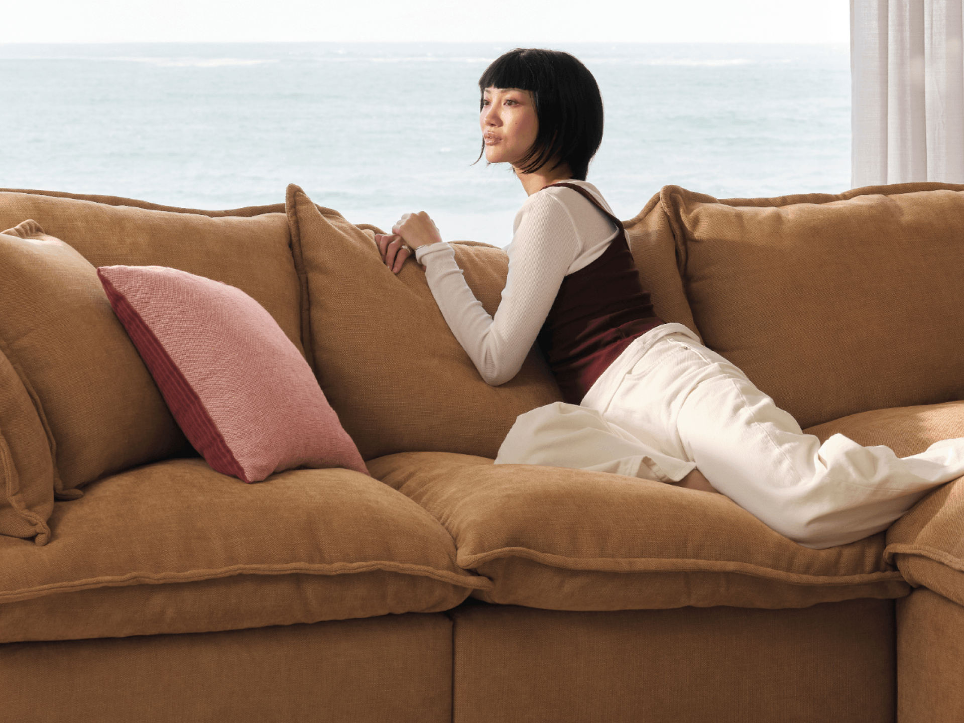 Koala Tamarama 4-section double-chaise modular sofa in Bronzed Aussie, with two models reclining and terracotta cushion