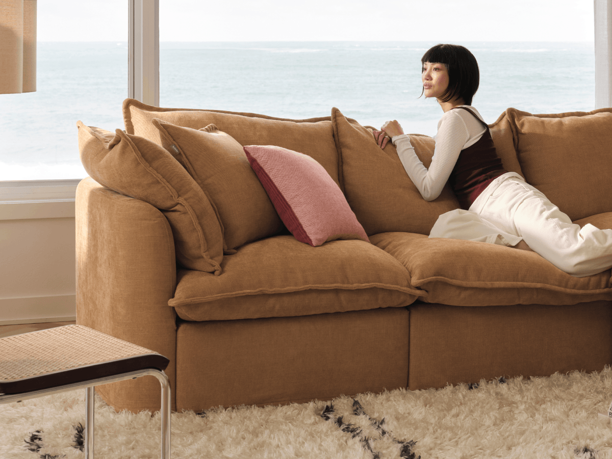 Koala Tamarama 4-section chaise modular sofa in Bronzed Aussie, with two models reclining and terracotta cushion