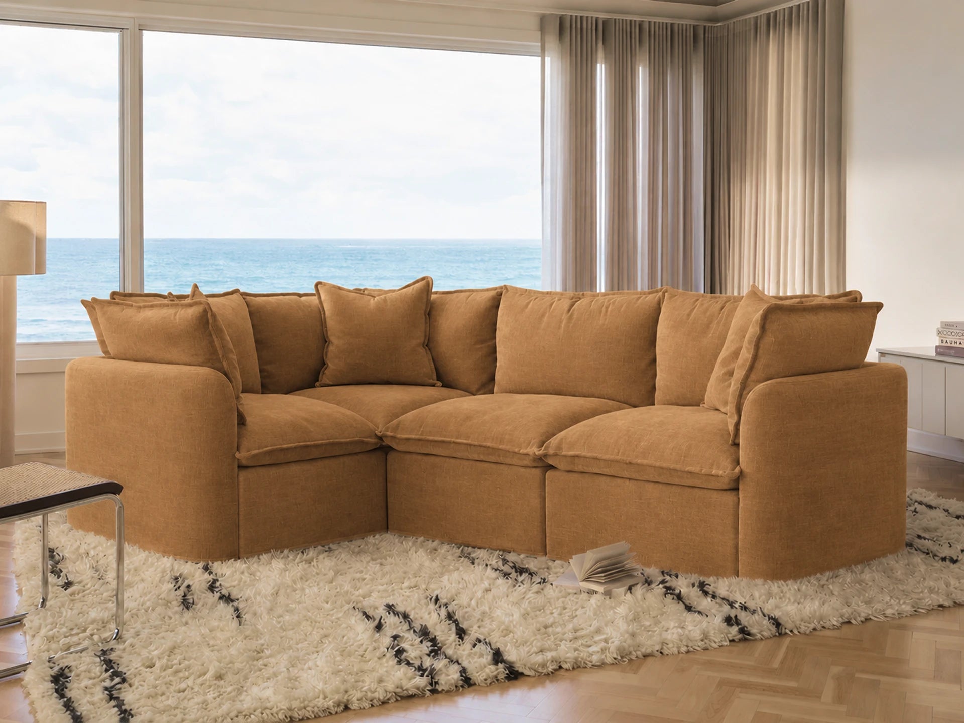 Brown sectional sofa in a living room with large windows overlooking the ocean.