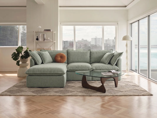 Modern living room with a green sectional sofa, coffee table, and decorative items.
