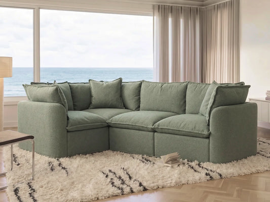 Green sectional sofa in a living room with large windows and ocean view.
