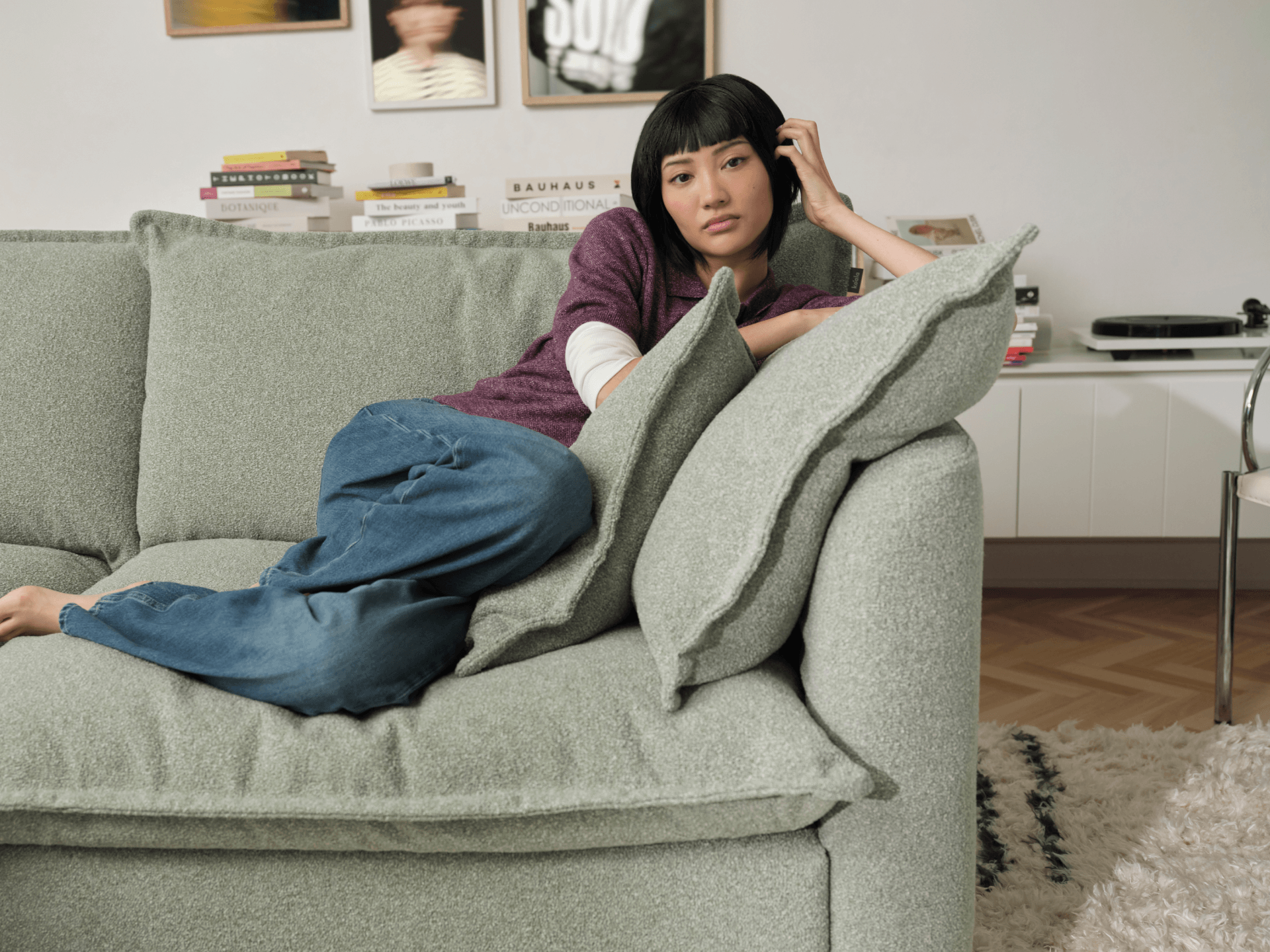 Koala Tamarama 6-section U-shape sectional in Frosty Grass, with model, brown knit cushion and bookshelves backdrop