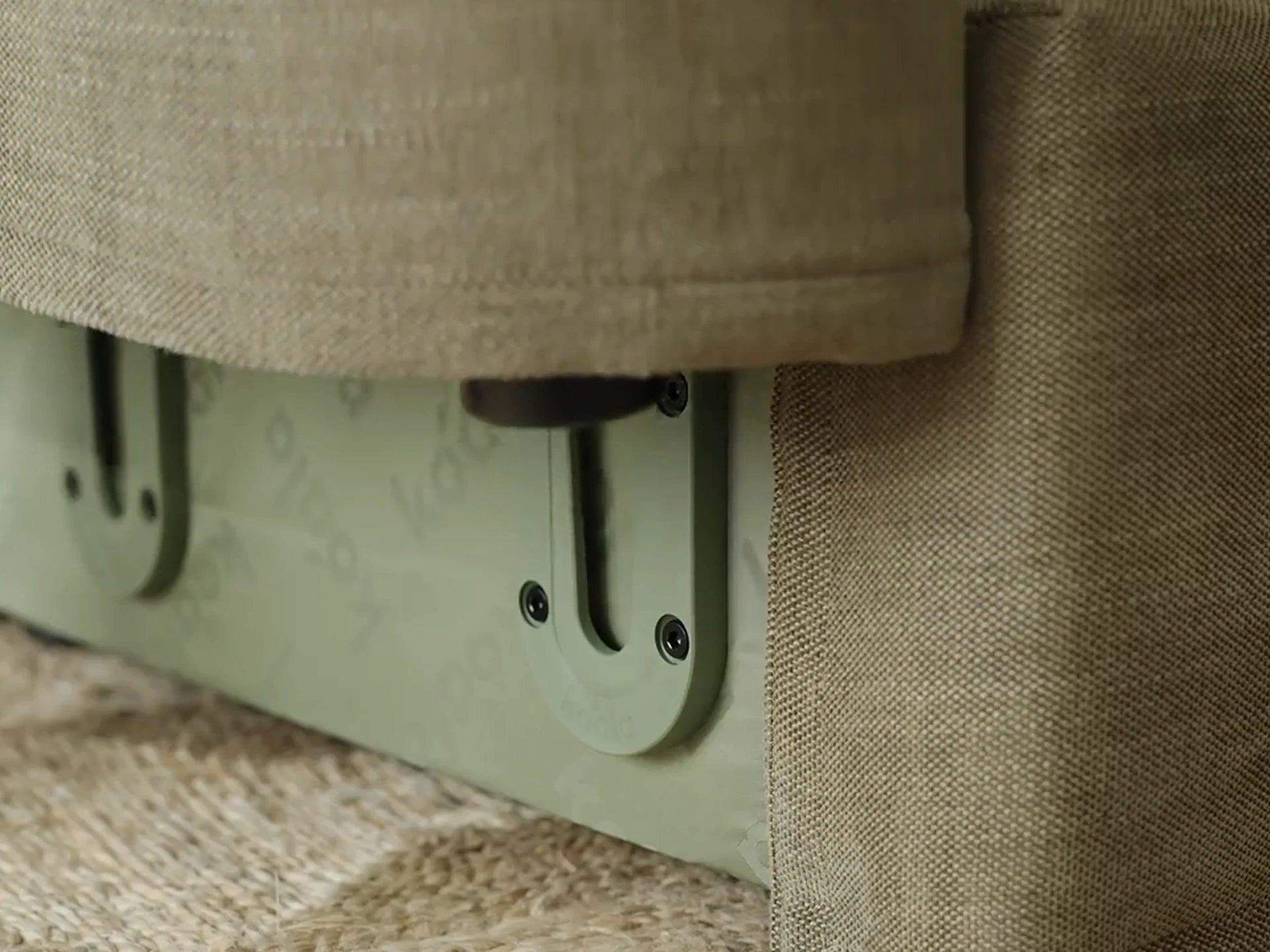 Close-up of a green metal bracket attached to green fabric.