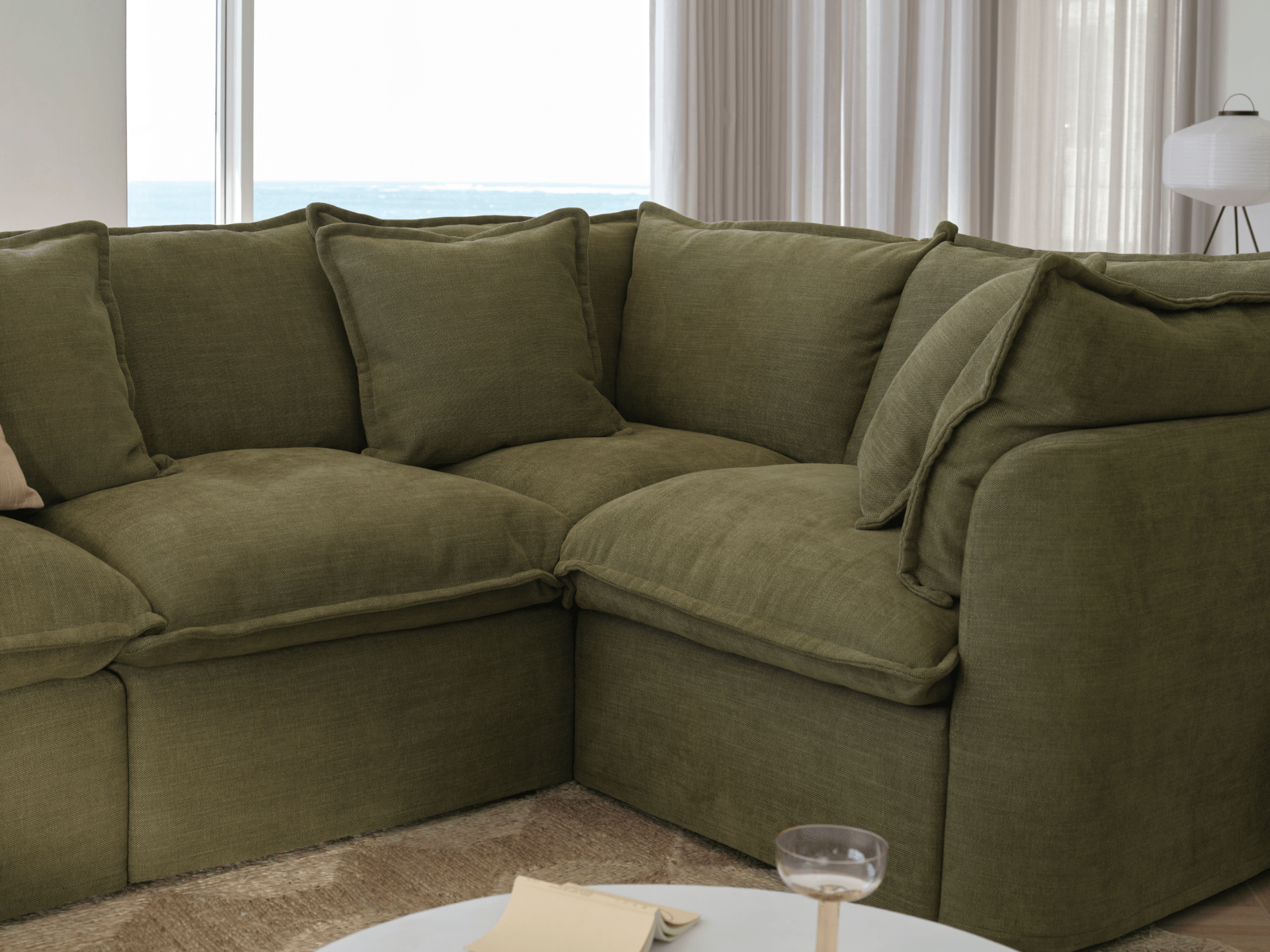 Koala Tamarama 6-section U-shape sectional in Forest Walk, with model, brown knit cushion and bookshelves backdrop