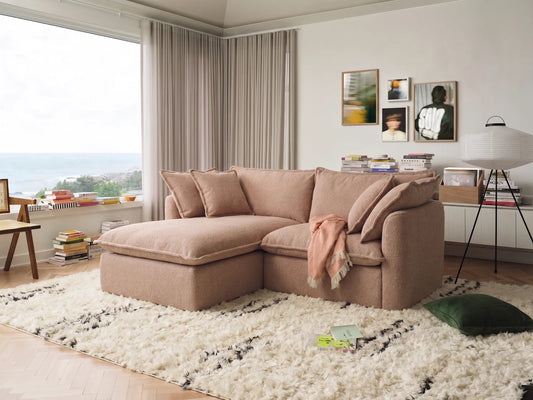 pebble beach sectional sofa in a living room with a large window, books, and decorative items.