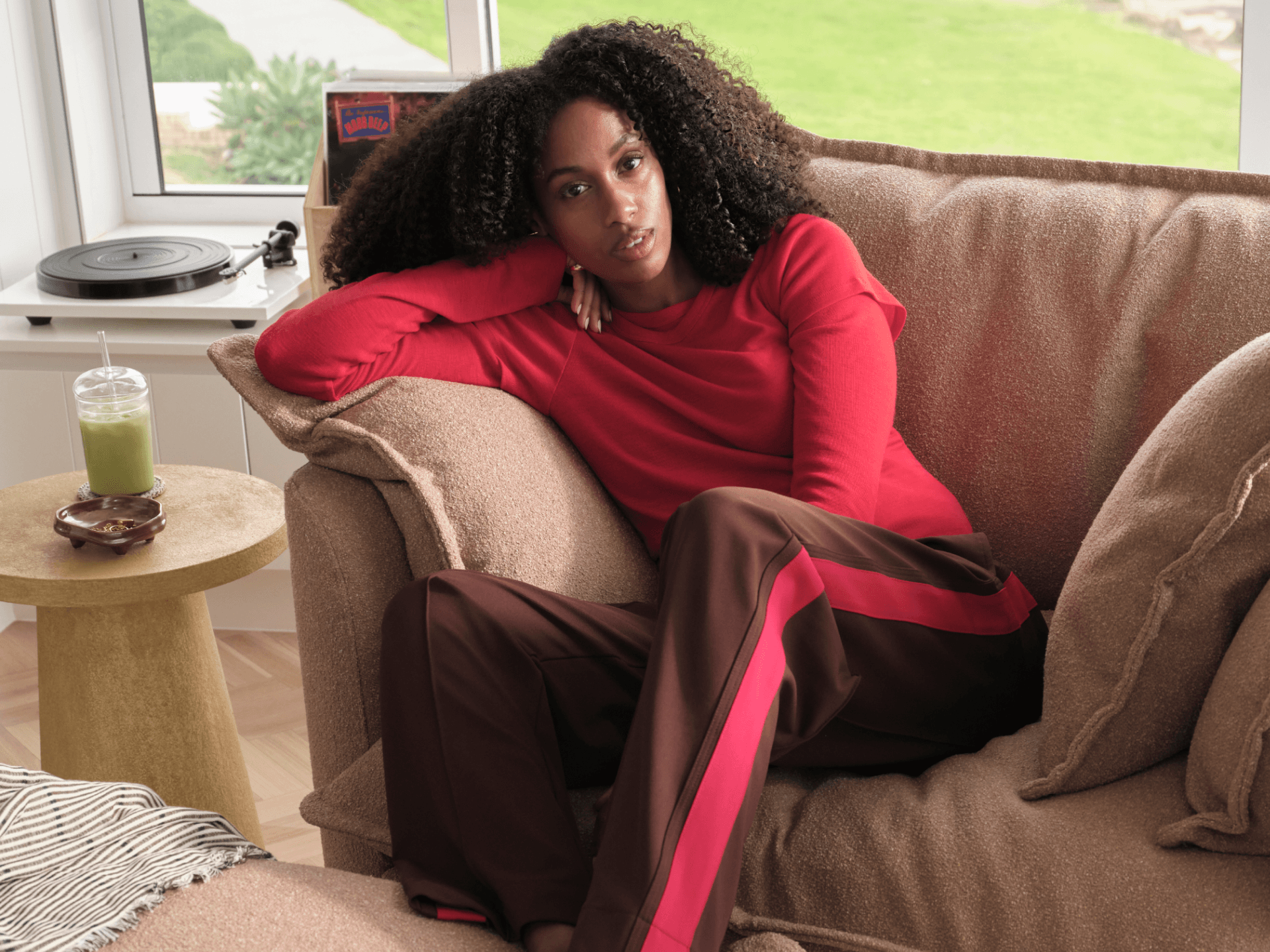 Koala Tamarama 4-section modular sofa in Pebble Beach, with model, brown knit cushion and bookshelves backdrop