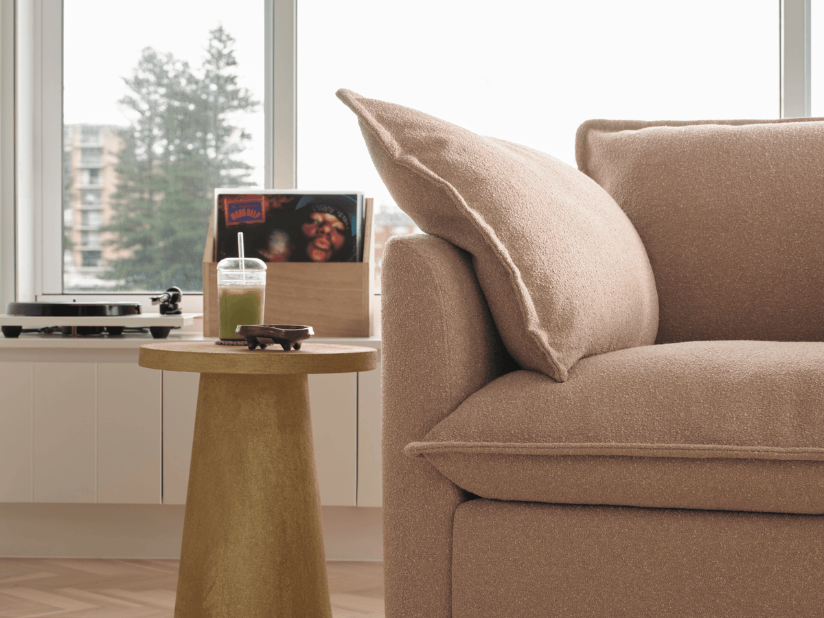 Koala Tamarama 6-section U-shape sectional in Pebble Beach, with model, brown knit cushion and bookshelves backdrop