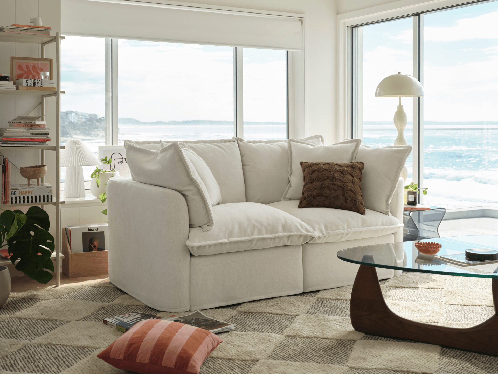 Living room with a white sofa and large windows overlooking water.