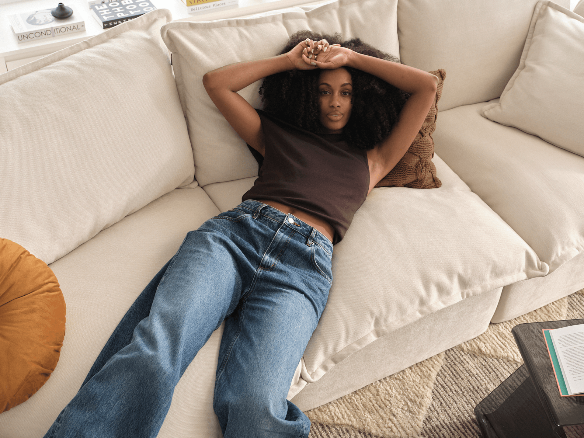 Woman relaxing on cream Koala modular sofa with cushions in styled living room overhead view