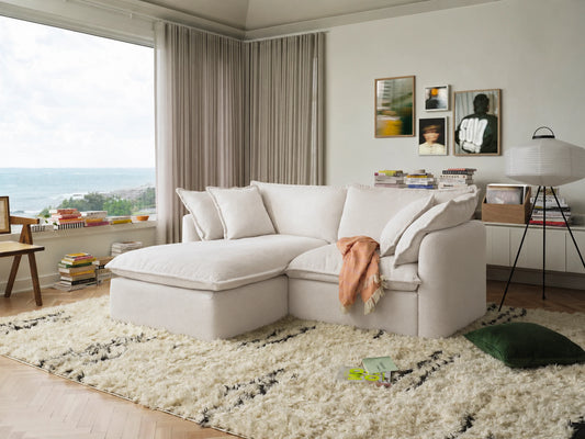 Modern living room with a white sectional sofa, plush rug, and decorative elements.