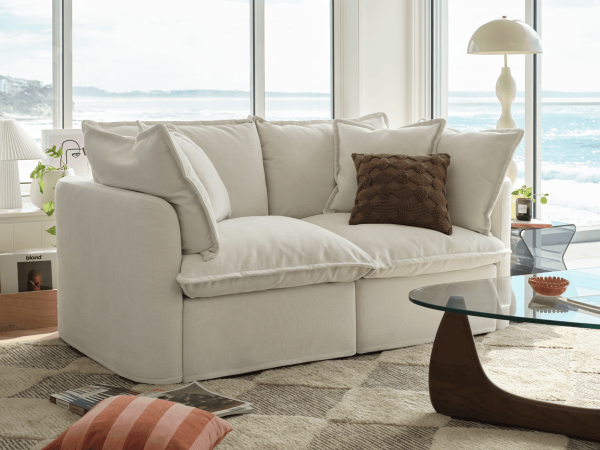 Koala Tamarama 2-section modular sofa in Winter Cream, in coastal living room with ocean view and glass table