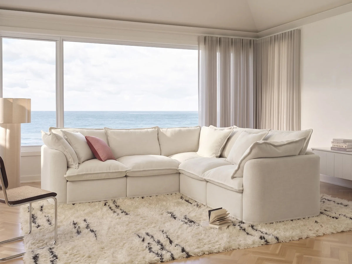 cream sectional sofa in a living room with large windows overlooking the ocean.