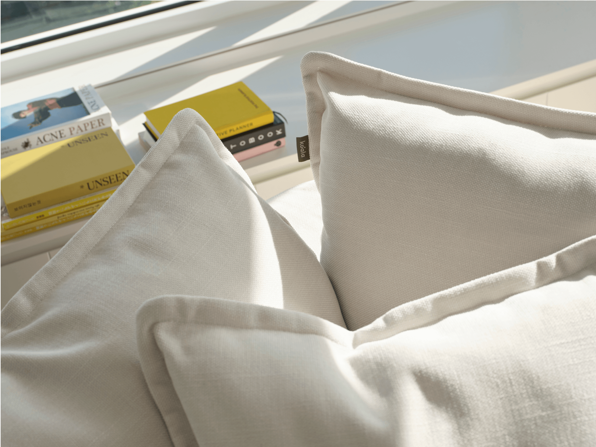 Koala Tamarama 6-section L-shape sectional in Winter Cream, linen scatter cushions with sunlit art books