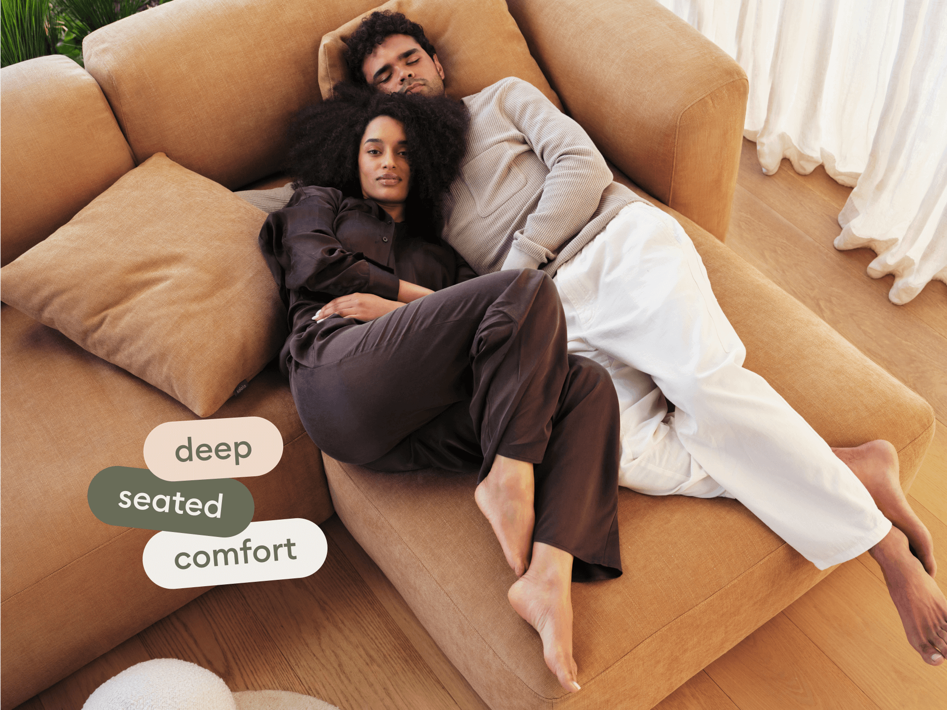 Luxurious L-shaped sofa in camel suede fabric. Features deep cushions and modular design. Set in a minimalist living room with light timber flooring.