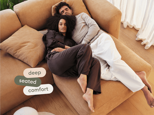 Luxurious L-shaped sofa in camel suede fabric. Features deep cushions and modular design. Set in a minimalist living room with light timber flooring.