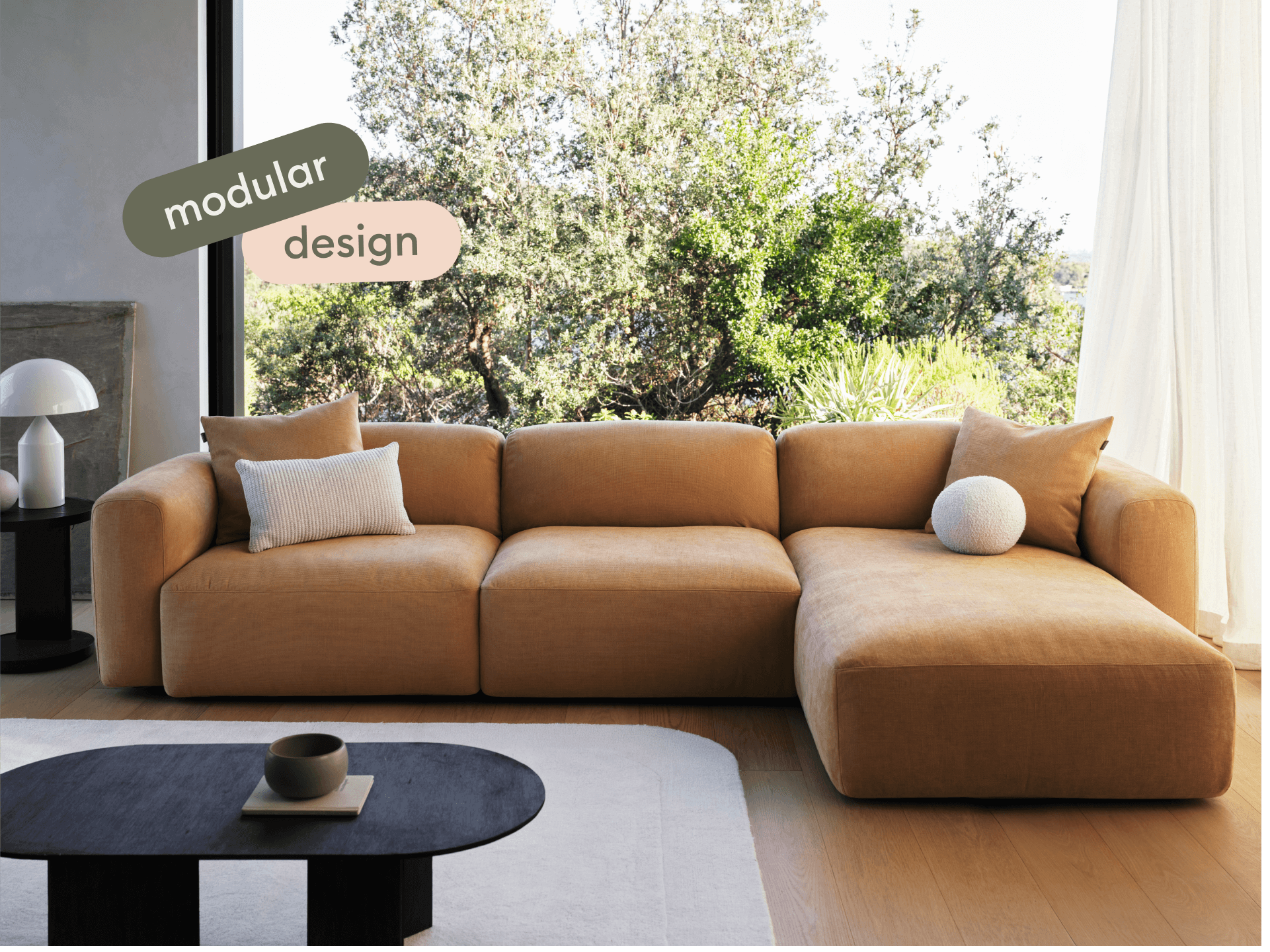 Luxurious modular sofa in warm ochre fabric, featuring plush cushions and low-profile design. Set in an elegant living area with natural light.