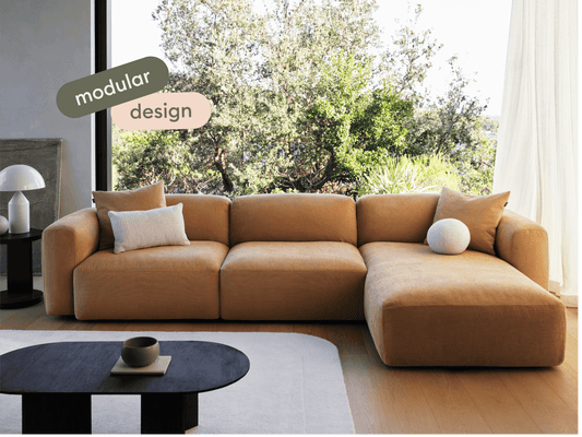 Luxurious modular sofa in warm ochre fabric, featuring plush cushions and low-profile design. Set in an elegant living area with natural light.