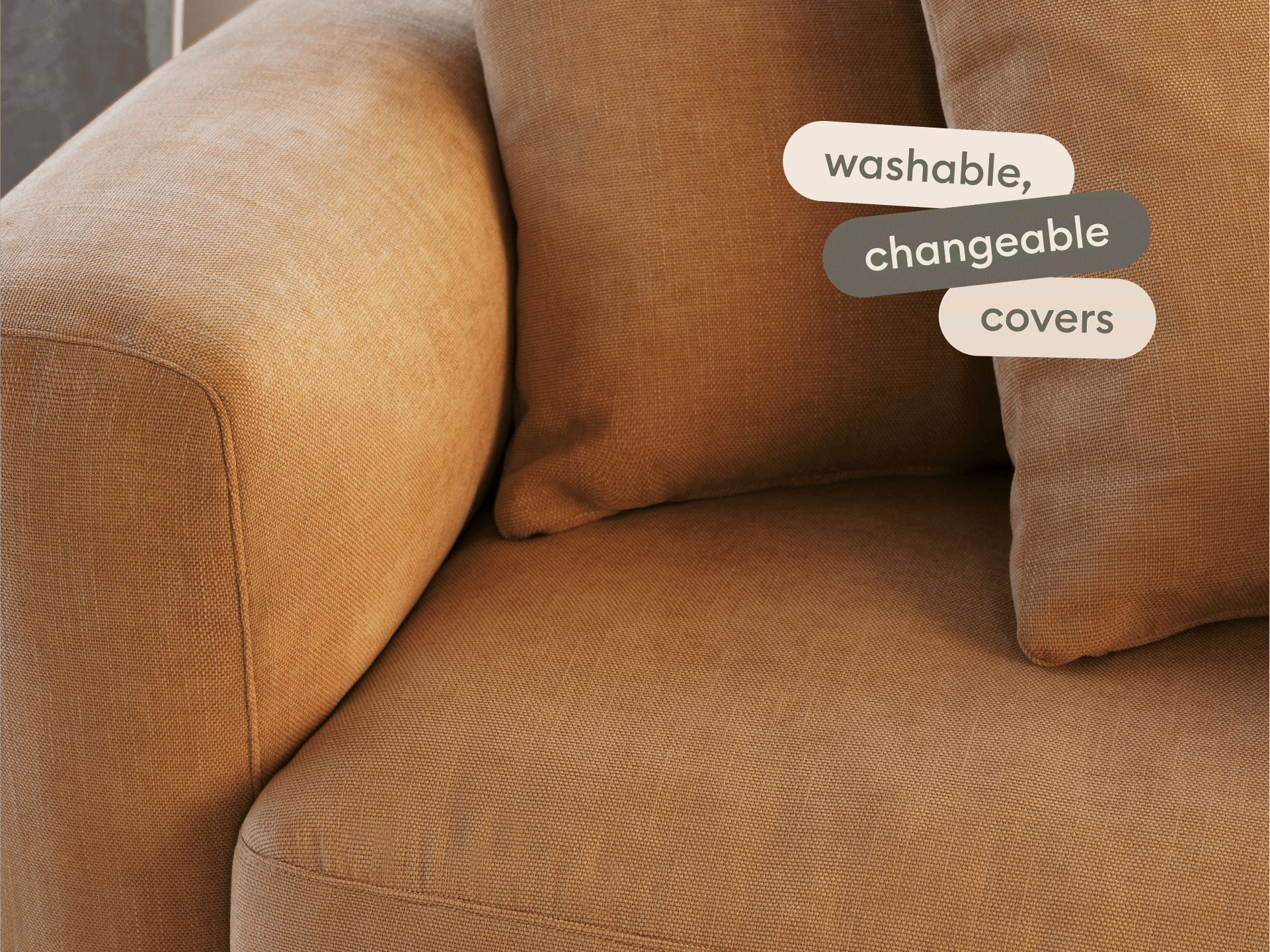 Modern sofa with plush, cinnamon-coloured fabric. Features washable, changeable covers. Set against a neutral backdrop for an elegant touch.