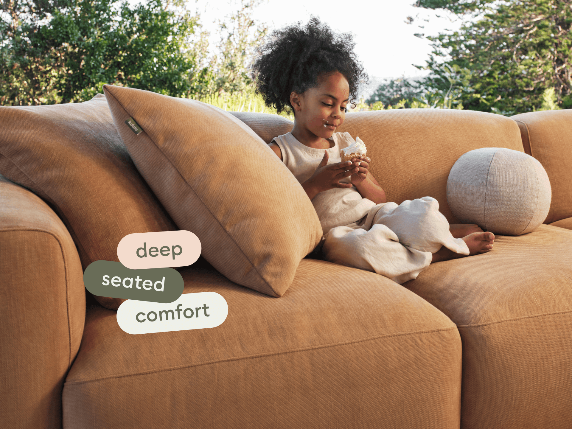 Luxurious deep-seated sofa in caramel fabric, featuring plush cushions and a contemporary design. Set in a serene outdoor environment.