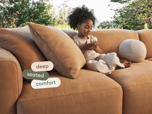 Luxurious deep-seated sofa in caramel fabric, featuring plush cushions and a contemporary design. Set in a serene outdoor environment.