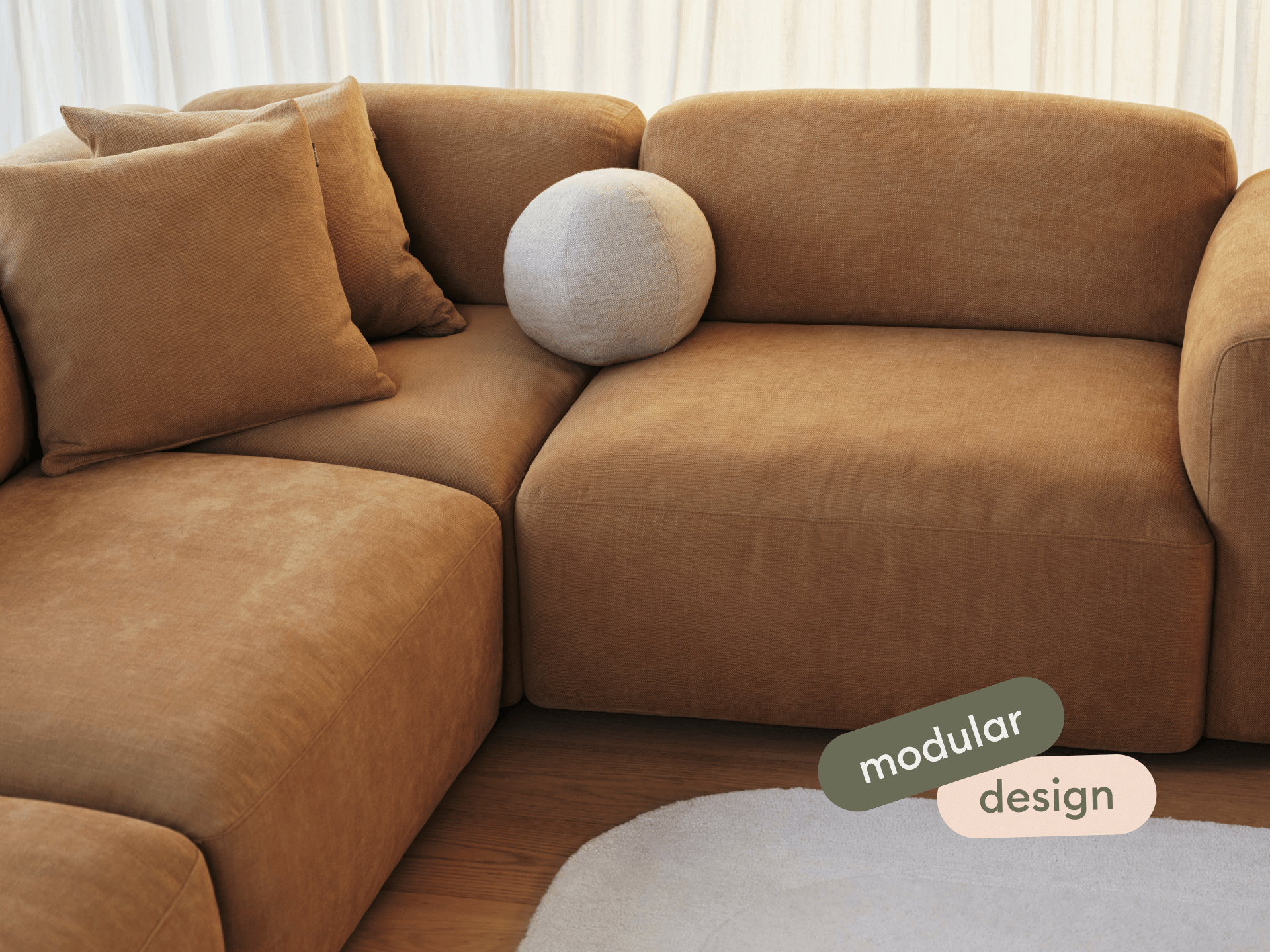 Luxurious modular sofa in rich brown suede, featuring plush cushions and a rounded armrest. Set on hardwood flooring with a soft, beige rug.