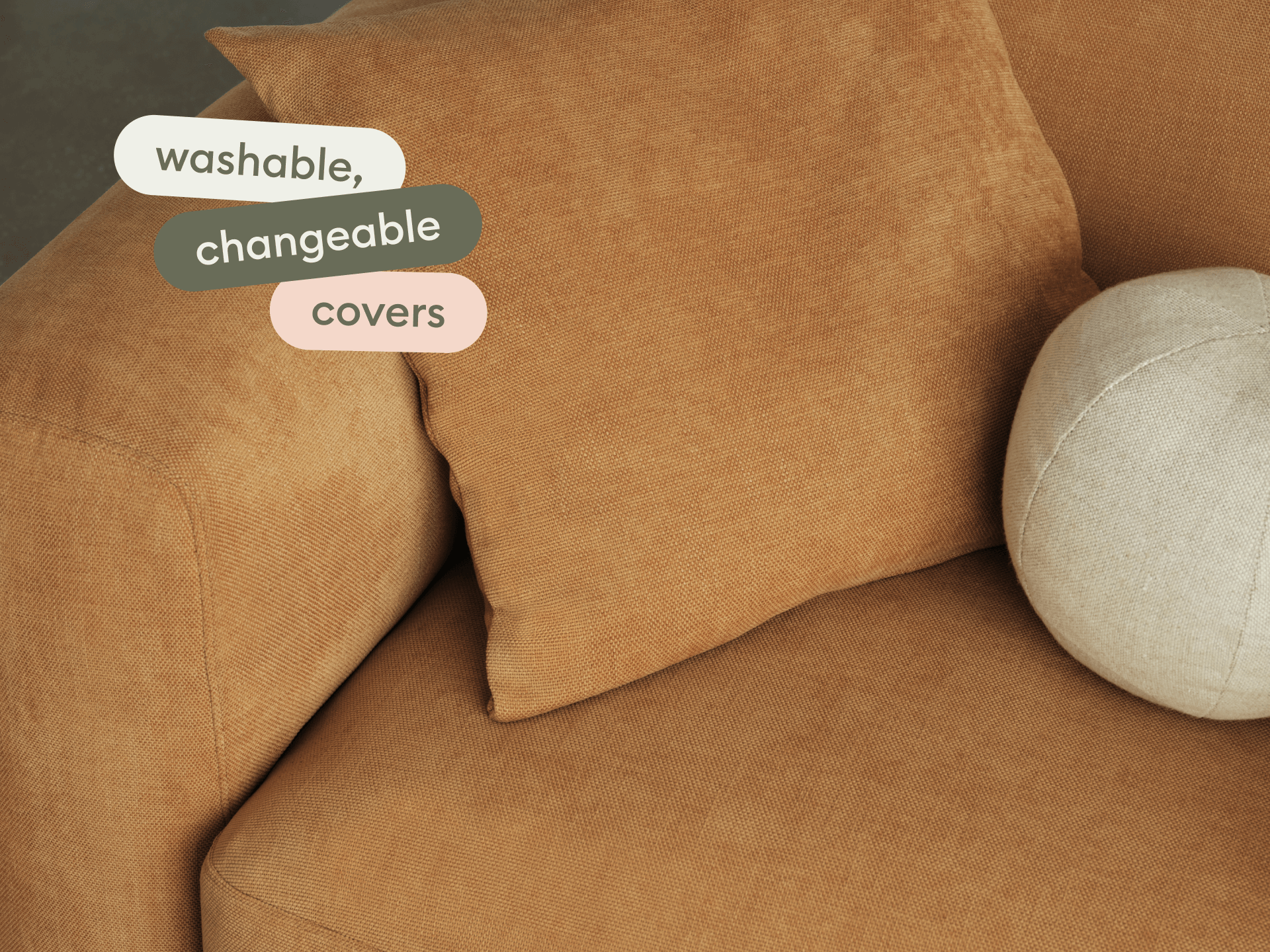Luxurious sofa in caramel fabric with washable, changeable covers. Features plush cushioning and rounded armrests. Styled with a round linen cushion.