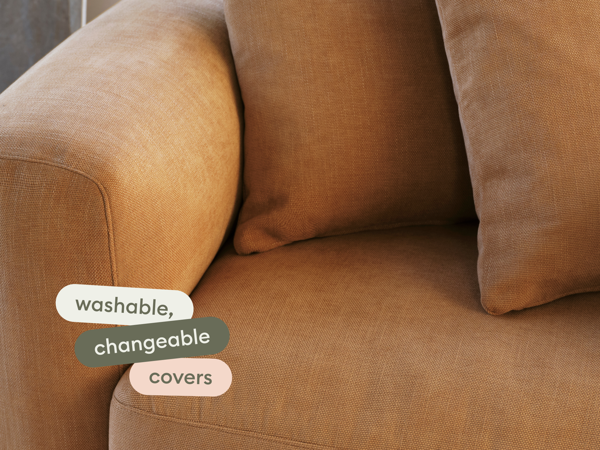 Luxurious tan linen sofa with curved armrest, featuring washable, changeable covers. Set in a modern living space, ideal for premium comfort.