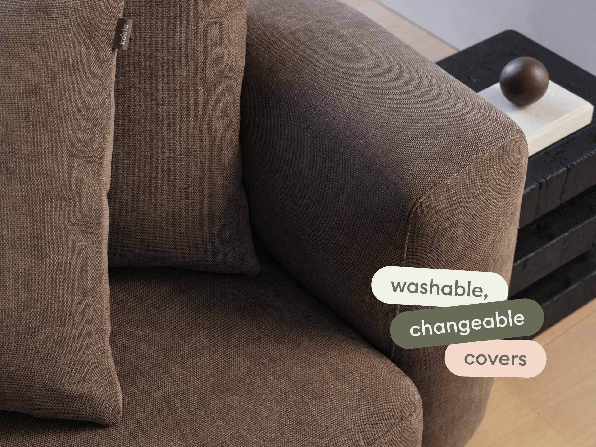 Luxurious brown fabric sofa with plush, washable, and changeable covers. Elegant box arm design, complemented by stacked dark side tables.